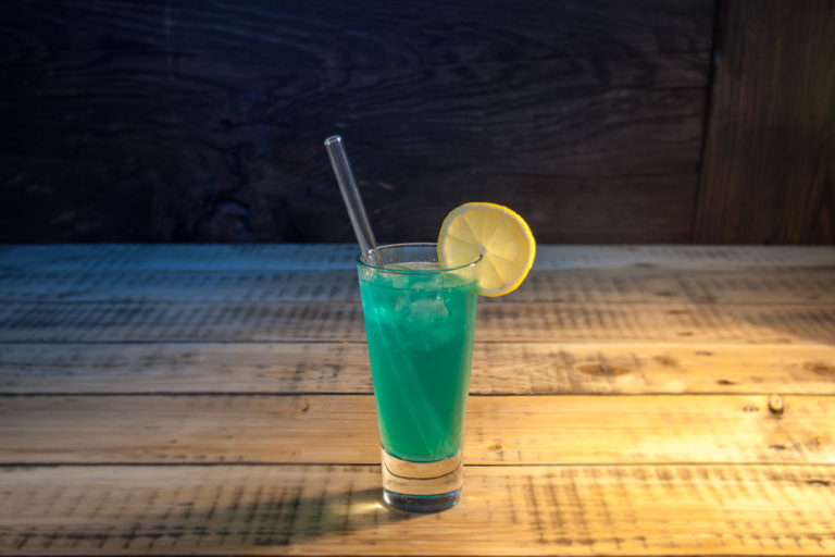 Cocktail Blue Lagoon in einem Glas mit Glas Trinkhalm